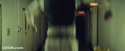 A Blurry Picture Of A Person Walking Down A Hallway With A Sign That Says Emergency Exit GIF