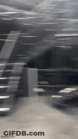 A Blurry Picture Of A Person Walking Down Stairs In A Dark Room . GIF