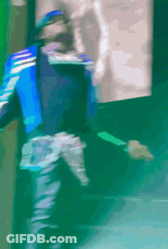 A Blurry Picture Of A Person Walking On A Green Floor GIF