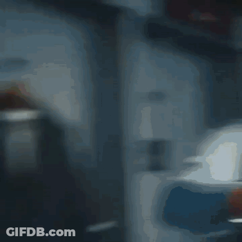 A Blurry Picture Of A Room With A Red Chair And A White Wall GIF
