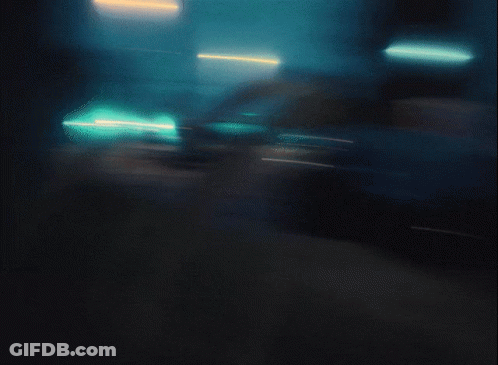 A Blurry Picture Of A Street At Night With Cars Parked On The Side Of The Road GIF