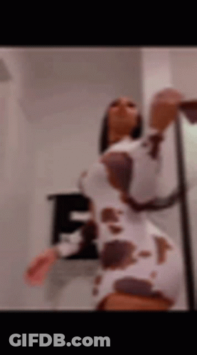 A Blurry Picture Of A Woman In A Cow Print Dress Dancing . GIF