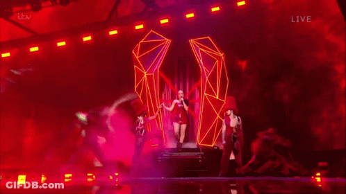 A Blurry Picture Of A Woman In A Red Dress On A Stage With Itv Live In The Lower Right Corner GIF
