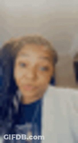 A Blurry Picture Of A Woman 'S Face With A Blue Shirt On . GIF