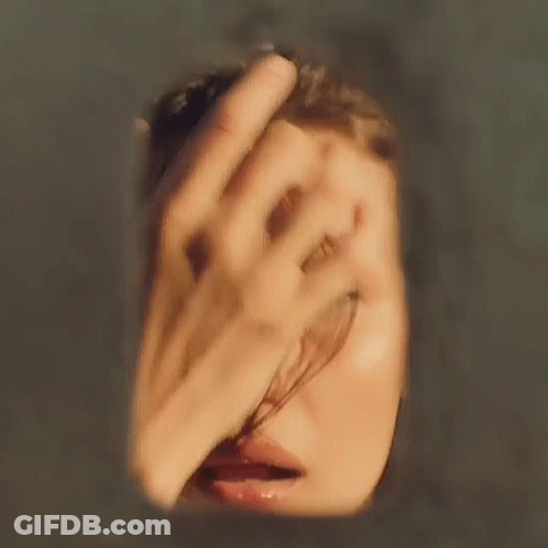 A Blurry Picture Of A Woman 'S Face With A Hand Covering Her Face GIF