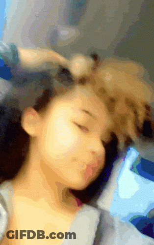 A Blurry Picture Of A Woman Sleeping With Her Eyes Closed And A Dog Laying On Her Head GIF