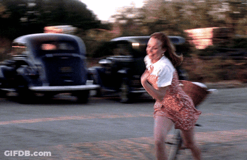 A Blurry Picture Of A Woman Walking Down A Street With A Car In The Background GIF