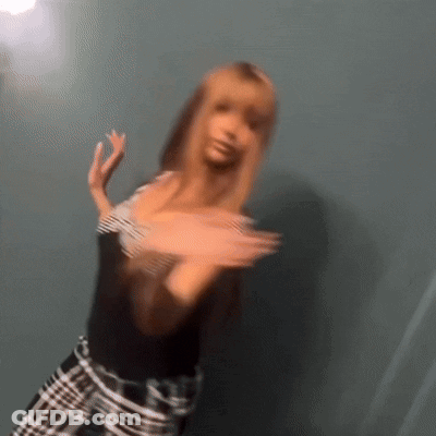 A Blurry Picture Of A Woman Wearing A Black Shirt And Plaid Pants GIF