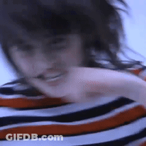 A Blurry Picture Of A Woman Wearing A Striped Shirt With Her Hair Blowing In The Wind . GIF