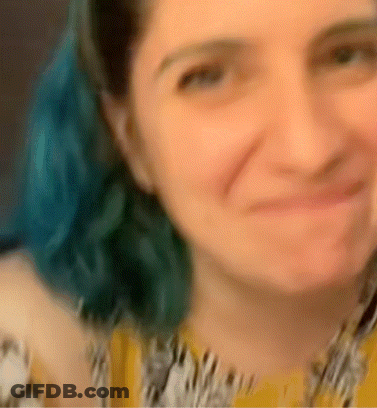 A Blurry Picture Of A Woman With Blue Hair And A Yellow Shirt GIF