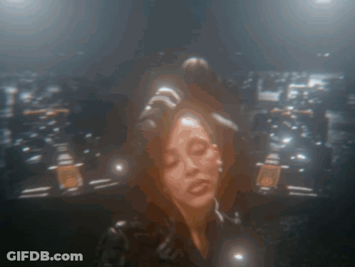 A Blurry Picture Of A Woman With Her Eyes Closed In A Dark Room GIF