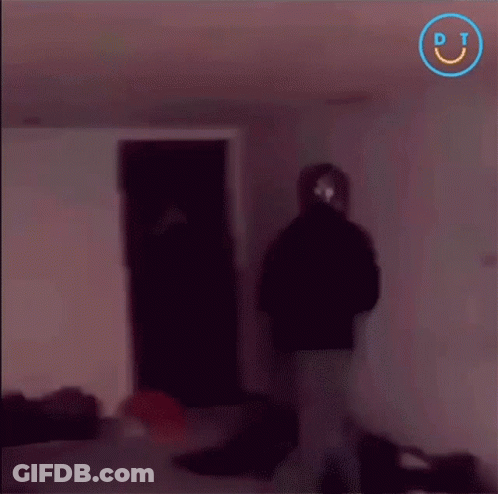 A Blurry Picture Of People In A Dark Room With A Smiley Face In The Corner GIF