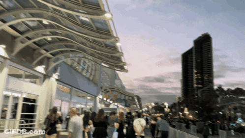 A Blurry Picture Of People Walking In Front Of A Building With A Sign That Says ' Sd Convention Center ' On It GIF