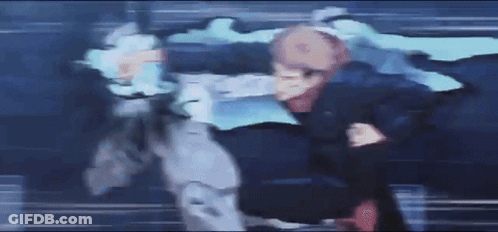 A Blurry Picture Of Two People Fighting Each Other In A Dark Room GIF