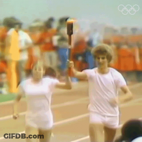 A Blurry Picture Of Two People Running With A Torch In Their Hands GIF