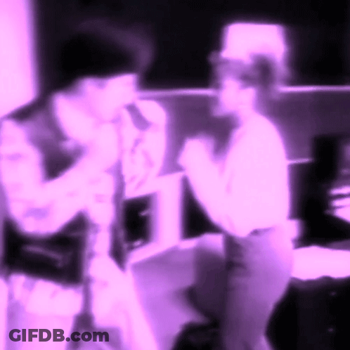 A Blurry Picture Of Two People Standing Next To Each Other In Purple Lighting GIF