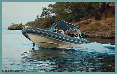 A Boat Is Floating On A Body Of Water Near A Cliff GIF