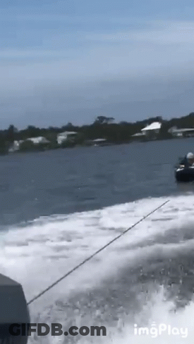 A Boat Is Going Through A Body Of Water With Houses In The Background GIF