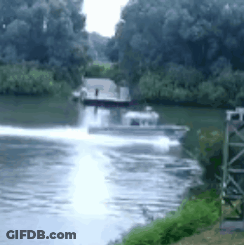 A Boat Is Speeding Down A River With Trees On The Shore GIF