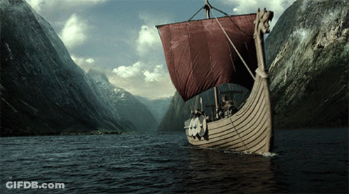 A Boat With A Red Sail Is In The Middle Of A River GIF
