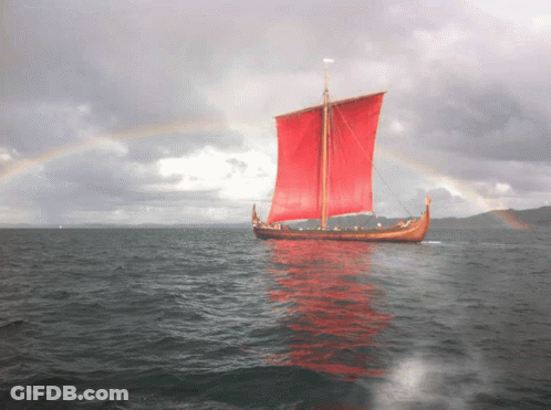A Boat With Red Sails Is In The Ocean GIF