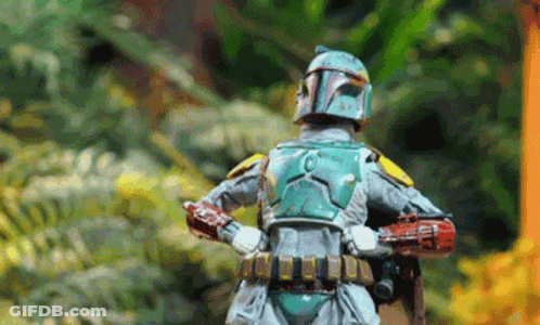 A Boba Fett Action Figure Is Standing In The Woods With His Arms Crossed . GIF