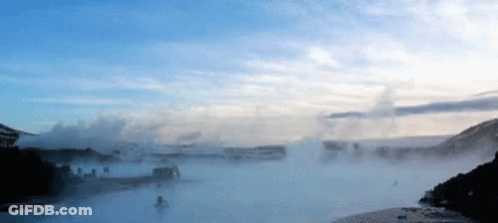 A Body Of Water With A Blue Sky And Clouds Behind It GIF