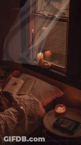 A Book On A Table Next To A Window With Candles And A Pumpkin GIF