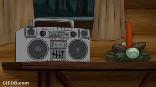 A Boombox Sits On A Wooden Table Next To A Red Candle GIF