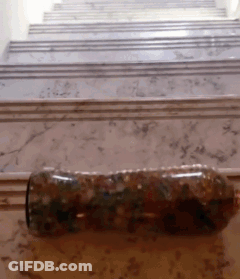 A Bottle Is Sitting On A Marble Floor In Front Of Stairs GIF