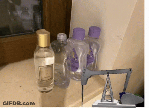 A Bottle Of Baby Oil Sits Next To A Bottle Of Perfume GIF