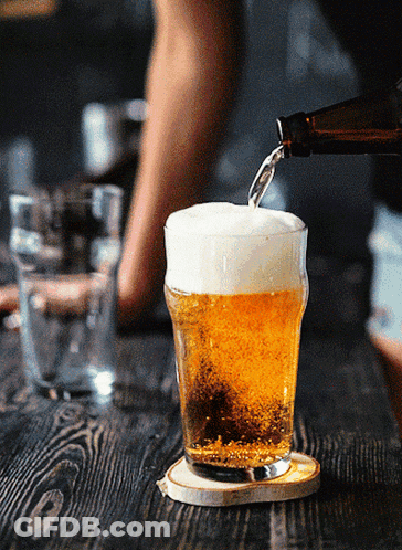 A Bottle Of Beer Is Poured Into A Glass On A Wooden Table GIF