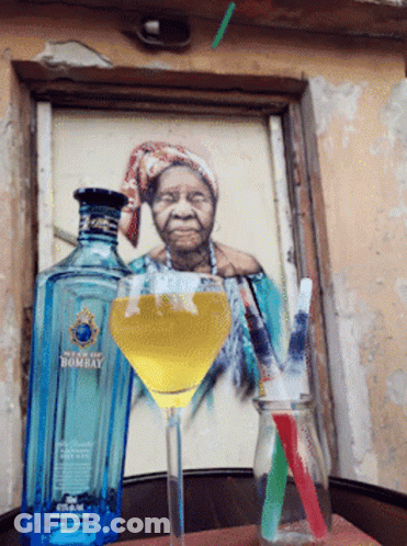 A Bottle Of Bombay Sits Next To A Martini Glass With A Straw GIF