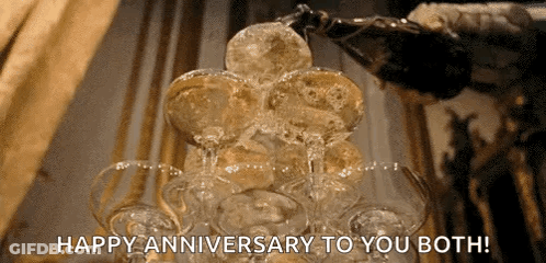 A Bottle Of Champagne Is Poured Into A Stack Of Champagne Glasses With The Words Happy Anniversary To You Both GIF