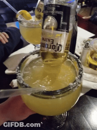 A Bottle Of Corona Is Being Poured Into A Margarita Glass GIF