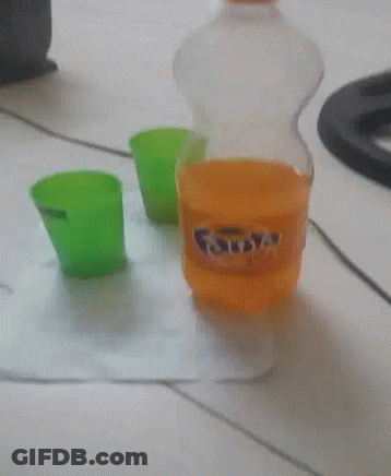 A Bottle Of Fanta Sits On A Table Next To A Green Cup GIF