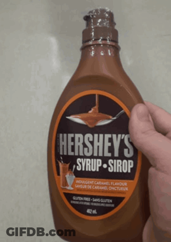 A Bottle Of Hershey 'S Syrup Is Being Held By A Hand GIF