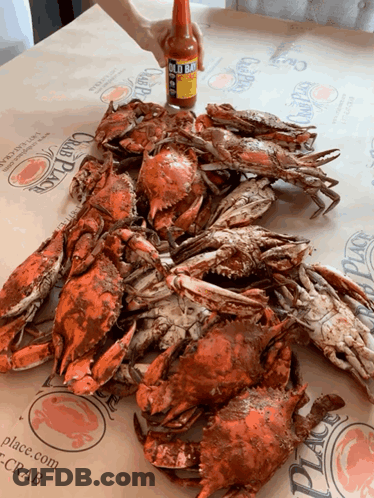 A Bottle Of Hot Sauce Is Being Poured Over Crabs GIF