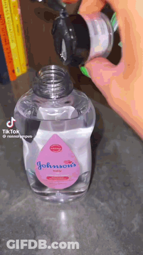 A Bottle Of Johnson 'S Baby Oil Is Being Poured Into Another Bottle GIF