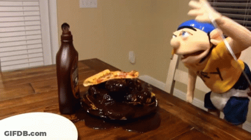 A Bottle Of Ketchup Sits On A Table Next To A Puppet With The Letter Y On His Shirt GIF
