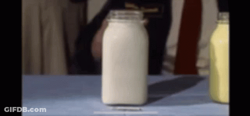 A Bottle Of Milk Is Sitting On A Table Next To Other Bottles GIF