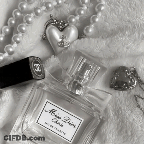 A Bottle Of Miss Dior Cherie Eau De Toilette Next To A Chanel Lipstick And Pearls GIF
