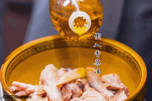 A Bottle Of Oil Is Being Poured Into A Bowl Of Meat GIF