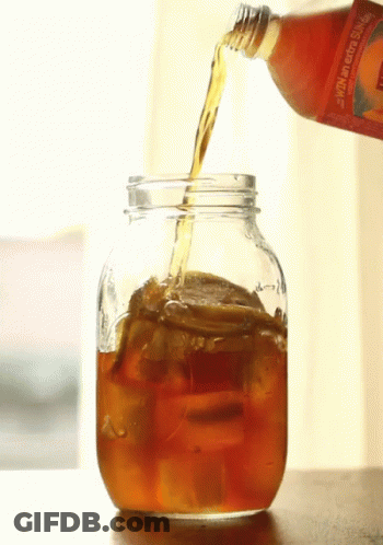 A Bottle Of Orange Juice Is Poured Into A Glass Jar GIF