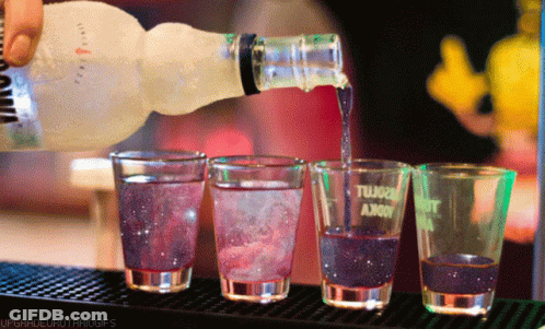 A Bottle Of Vodka Is Poured Into Shot Glasses GIF