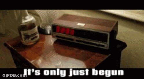 A Bottle Of Whiskey Sits Next To An Alarm Clock That Reads 8:08 GIF