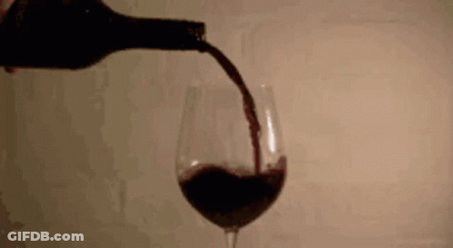 A Bottle Of Wine Is Being Poured Into A Glass Of Wine GIF
