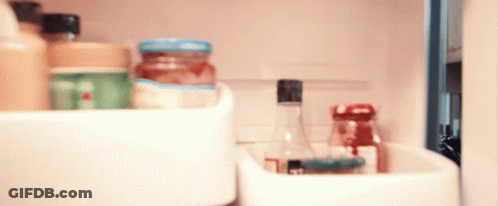 A Bottle With A Black Cap Sits In A Refrigerator Shelf GIF