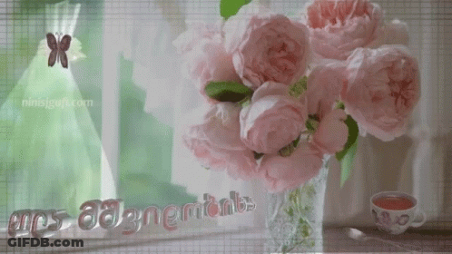 A Bouquet Of Pink Flowers In A Vase With A Cup Of Tea And A Butterfly GIF
