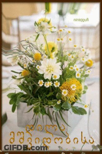A Bouquet Of Yellow And White Daisies In A Silver Vase With The Name Ninisjgufi On The Bottom GIF